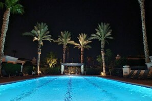 Ein Pool mit Palmen und Liegestühlen.
