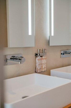 A bathroom with a large white bathtub, a mirror above it, and two bottles of hand soap on the wall. - New Sea-View Villa w/ Private Pool & Jacuzzi – SXM - Villa Maé (St Martin)