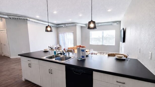 A modern kitchen with a central island, two pendant lights, and a dishwasher. - Family-Friendly 2BR with Amenities, WiFi & Parking (Des Moines)