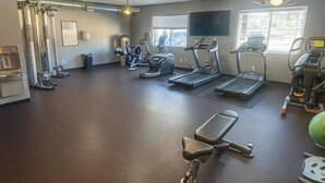 Une salle de sport équipée de tapis de course, de vélos elliptiques et d’un appareil d’aviron.