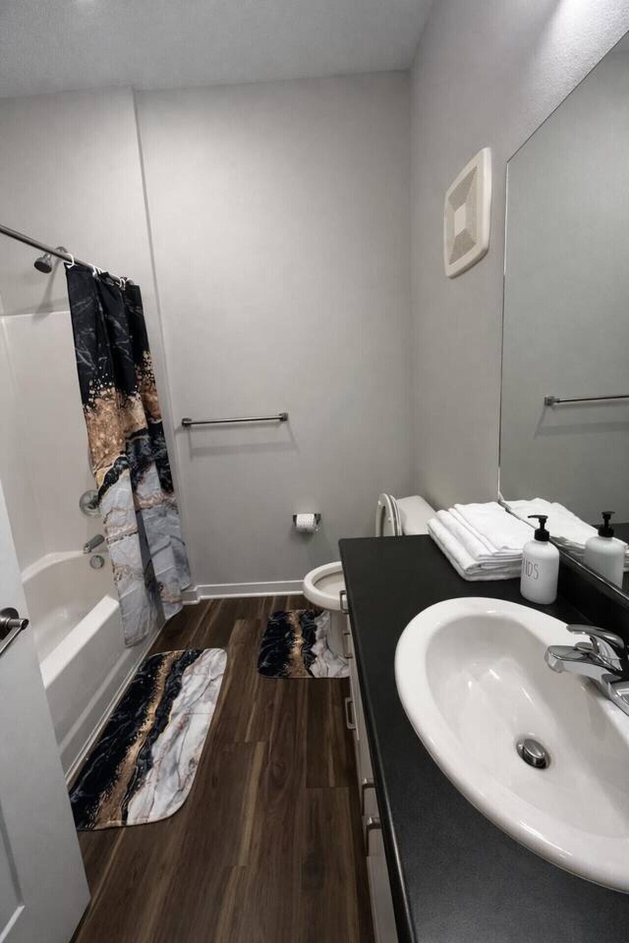 A bathroom with a bathtub, toilet, sink, and a shower curtain.