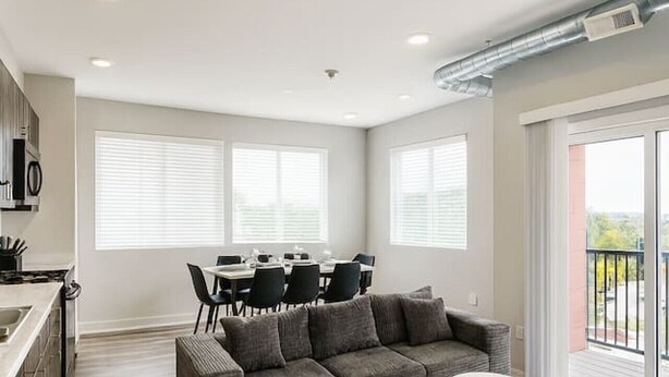 A modern apartment with a kitchen, dining area, and a large gray sectional sofa. - Elegant 2BR Apartment with Fast WiFi & Free Parking (Des Moines)