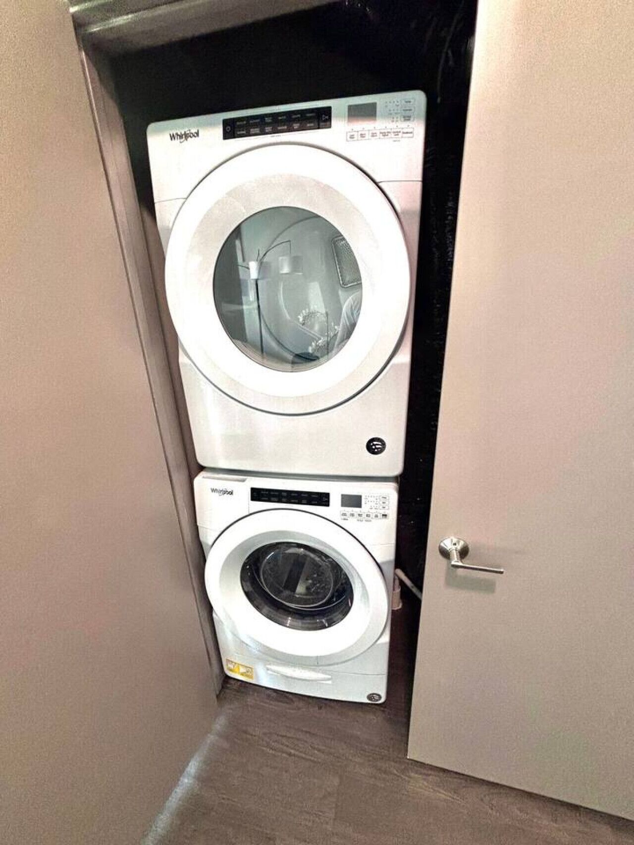 En tvättmaskin och en torktumlare från Whirlpool, placerade ovanpå varandra i en smal hall.