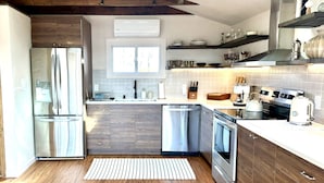 Eine moderne Küche mit Edelstahlgeräten, Holzschränken und einem Fenster über der Spüle.