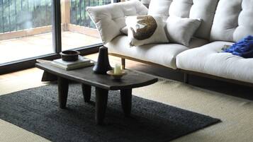 A modern living room with a sofa, a coffee table, and a view of a balcony.