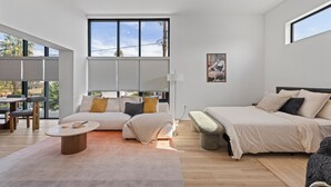 A modern, well-lit bedroom with a large bed, a sofa, and a dining area. - Cozy / New 2-bedroom apartment in North Hollywood (Los Angeles)