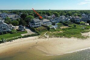 Eine Luftaufnahme einer Küstenwohngegend mit Häusern, einem Strand und einem Leuchtturm.