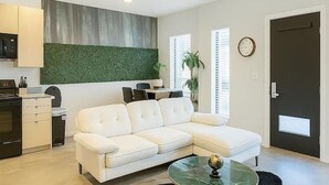 Een moderne woonkamer met een witte bank, een glazen salontafel en een donzig zwart vloerkleed.