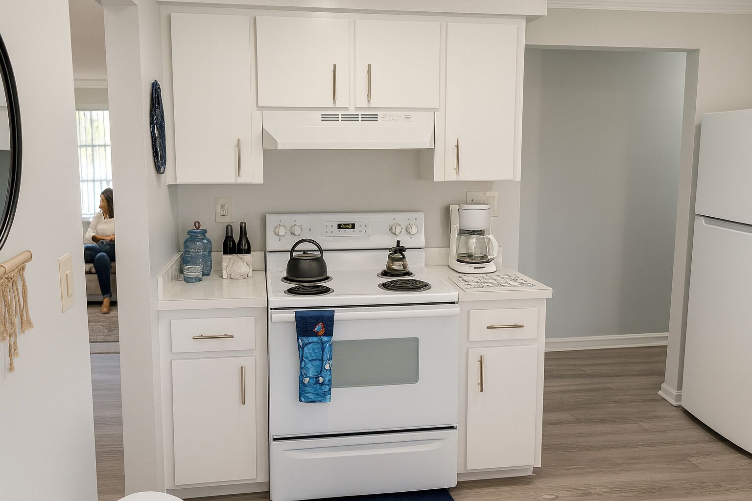 A compact kitchen with white cabinetry, a stove, a coffee maker, and a refrigerator.
