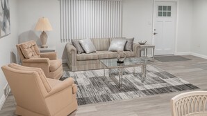 Un salon avec un canapé beige, deux fauteuils, une table basse et une lampe.