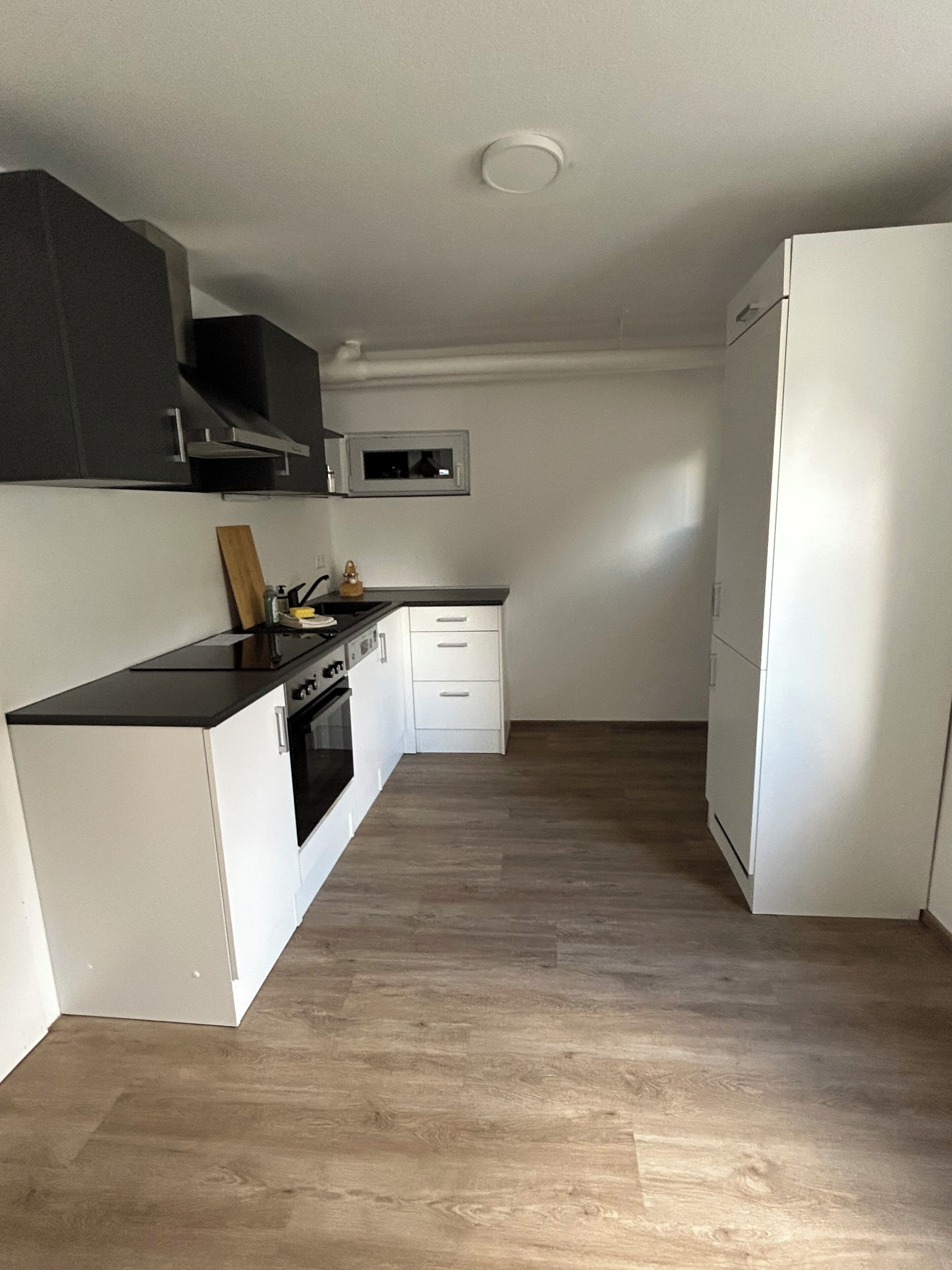 A compact kitchen with a microwave, oven, and white cabinetry.