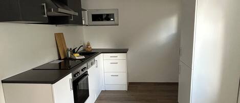 A compact kitchen with a microwave, oven, and white cabinetry.