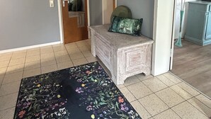 A room with a floral rug, a wooden bench with cushions, a framed picture on the wall, and a door leading to another room. - Feel-good vacation in Baden-Baden: Your vacation apartment (Baden-Baden)