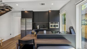 Uma cozinha moderna com armários escuros, eletrodomésticos de aço inoxidável e uma ilha central com assentos.