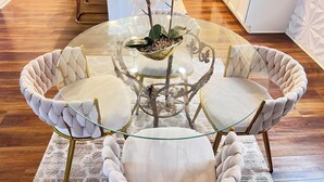 A round glass table with a central plant, surrounded by cushioned chairs.