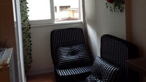 A small room with a window, a radiator, a black and white striped sofa, and a small table. - Cozy studio in Glória, close to the Lapa arches and Glória metro station. (Rio de Janeiro)