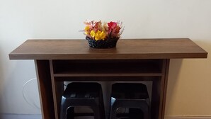 A wooden desk with two black stools and a basket of colorful flowers on top. - Cozy studio in Glória, close to the Lapa arches and Glória metro station. (Rio de Janeiro)
