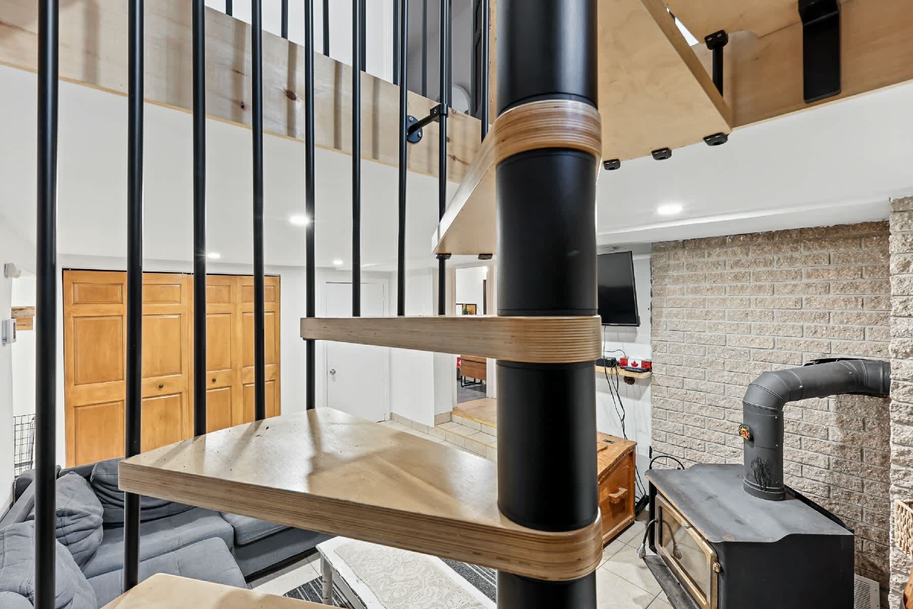 A modern interior with a staircase, a wooden table, and a black stove.