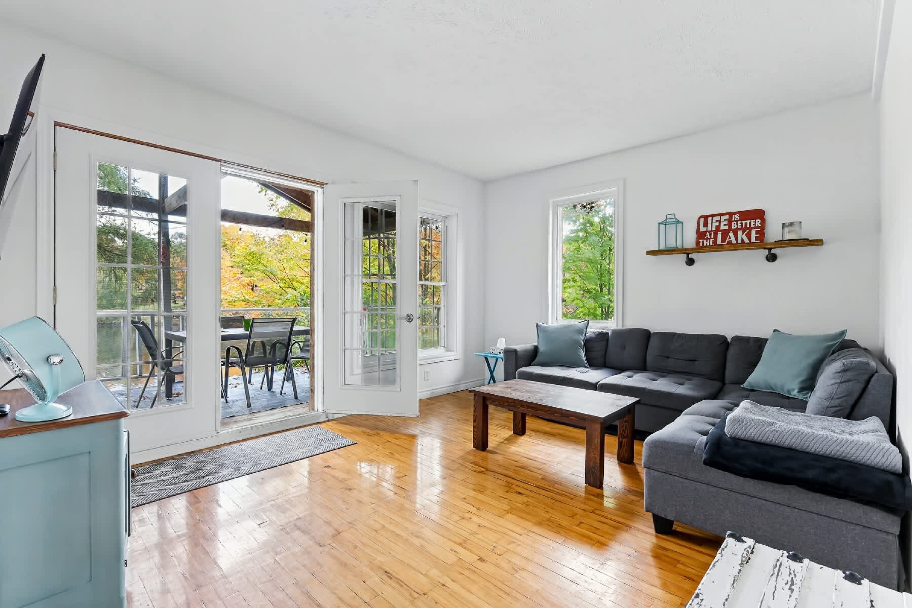 A spacious living room with a grey sofa, wooden coffee table, and a dining area with chairs and a table.