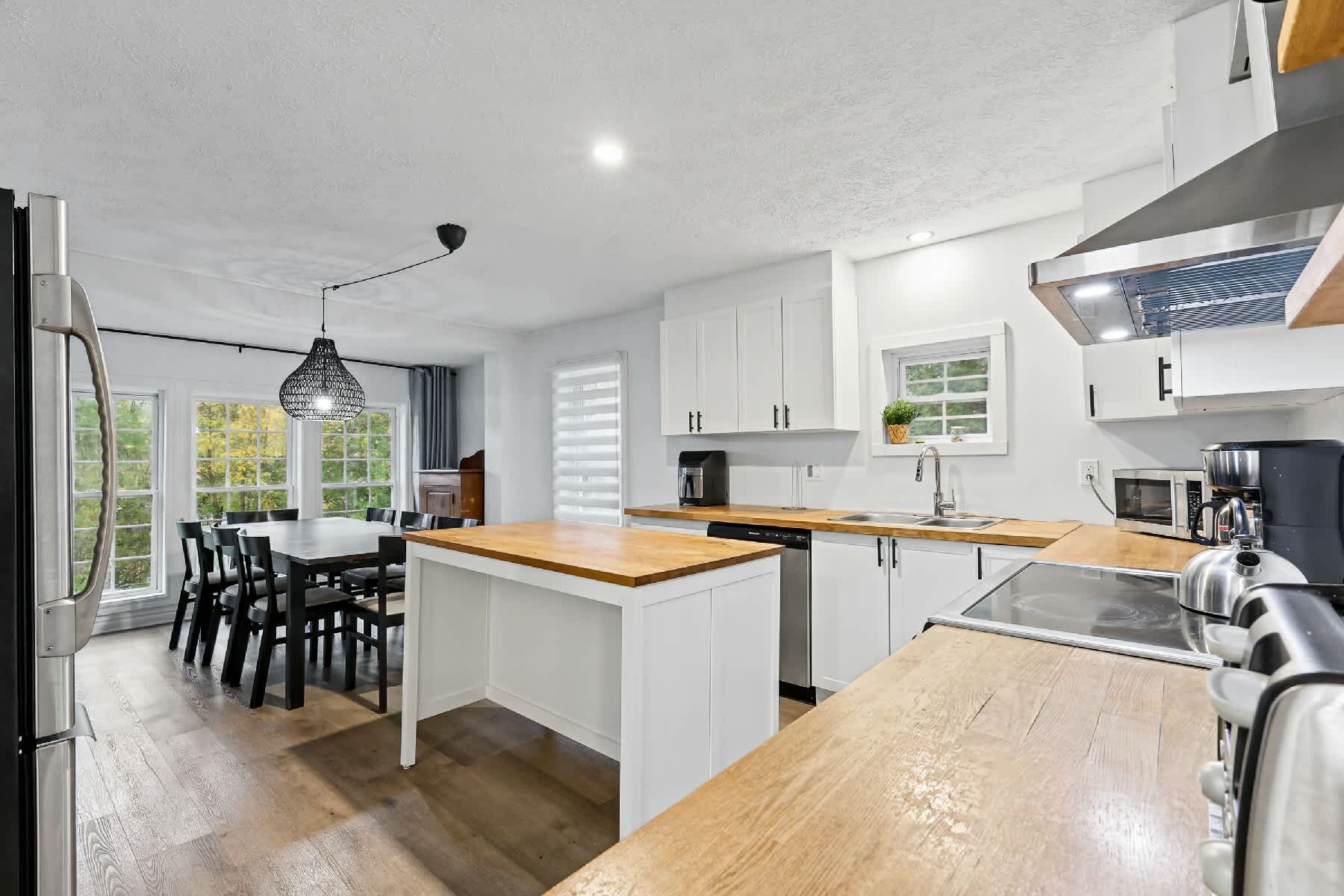 Una cocina moderna con armarios blancos, una isla de madera y un microondas integrado.