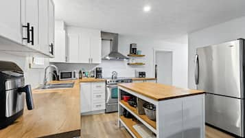 Una cocina moderna con armarios blancos, electrodomésticos de acero inoxidable y encimeras de madera.