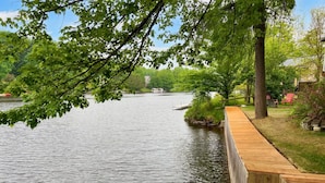 A wooden dock extending into a calm lake, surrounded by lush greenery and trees. - Lake Access - Private Spa - Pool table | Rustique (Saint-Claude)