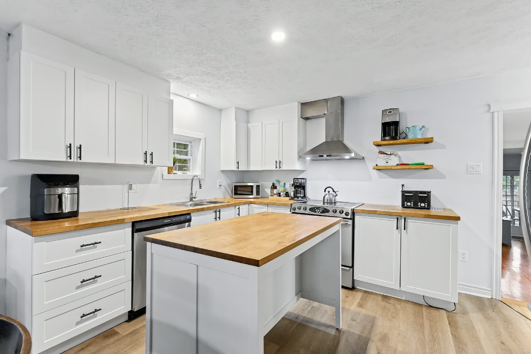 A modern kitchen with white cabinetry, a central island, and built-in appliances.