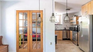 A modern kitchen with wooden cabinets, stainless steel appliances, and pendant lighting. - Lake Access - Private Spa - Pool table | Rustique (Saint-Claude)