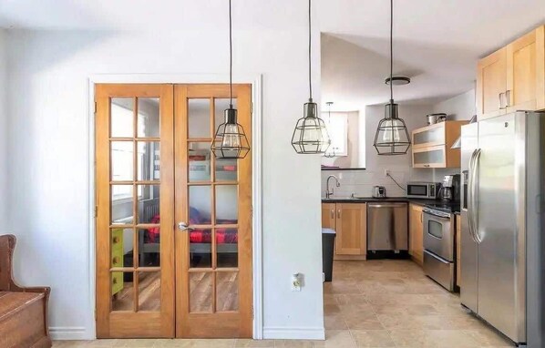 A modern kitchen with wooden cabinets, stainless steel appliances, and pendant lighting. - Lake Access - Private Spa - Pool table | Rustique (Saint-Claude)