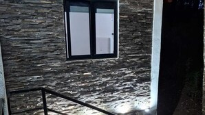 En moderne bygning med en stenfassade, et vindue og en trappe med gelændere i metal.