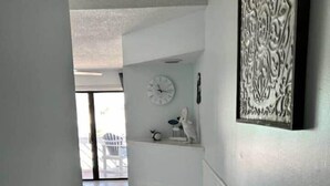 A narrow hallway with wooden flooring, white walls, and a decorative wall piece. - Cozy Coastal Condo in Murrells Inlet! (Garden City)