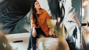 Une personne assise devant une grande fresque murale présentant des œuvres d’art à la fois abstraites et réalistes.