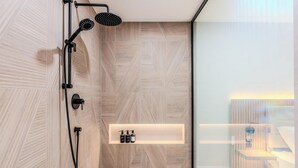 Une salle de bain moderne équipée d’une douche, d’un meuble-lavabo avec miroir et d’une étagère pour les articles de toilette.