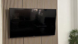 Ein Flachbildfernseher an einer Wand mit vertikalen Holzleisten.