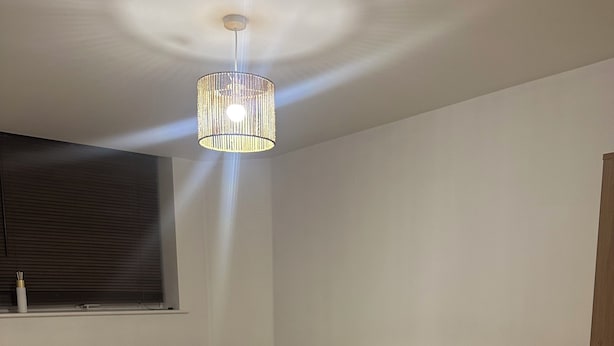 Ein Schlafzimmer mit Bett, Nachttisch, Lampe und einer Pendelleuchte.