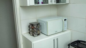 Une cuisine de taille réduite avec des meubles blancs, un four à micro-ondes et un porte-épices.