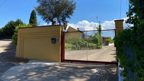 A gated entrance with a yellow wall and a metal gate. - Villa among olive trees with garden and parking • Relax in Puglia (Puglia)