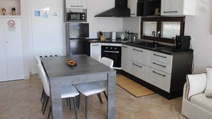 A compact kitchen with a dining table, chairs, a stove, oven, microwave, and a sink. - Villa among olive trees with garden and parking • Relax in Puglia (Puglia)