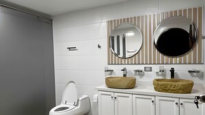 A modern bathroom with a toilet, a sink with a large basin, and two mirrors above the sink. - Apto Palos Altos  (Medellin)