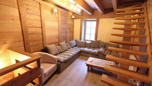 Ein gemütliches Blockhausschlafzimmer mit Holzvertäfelung, einer Couch, einem Sessel und einem kleinen Tisch.