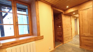 Ein Zimmer mit Fenster, Holzwänden, Heizkörper und Fliesenboden.
