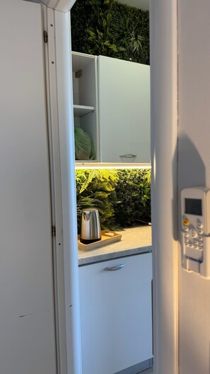 Une cuisine dotée d’un jardin d’herbes aromatiques intégré, d’une bouilloire en acier inoxydable et d’une machine à café moderne.