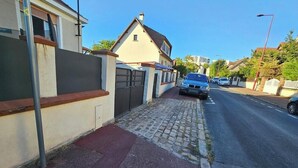 Una calle residencial con casas, aceras adoquinadas y coches aparcados.