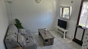 Una sala de estar moderna con un sofá, una mesa de centro, un televisor sobre un mueble bajo y una ventana con vistas.