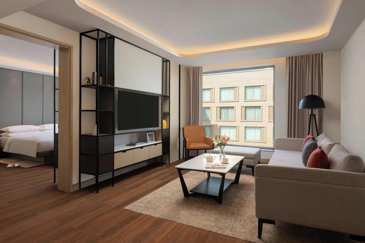 Een moderne hotelkamer met een bank, een bijzettafeltje, een televisie en een bed.