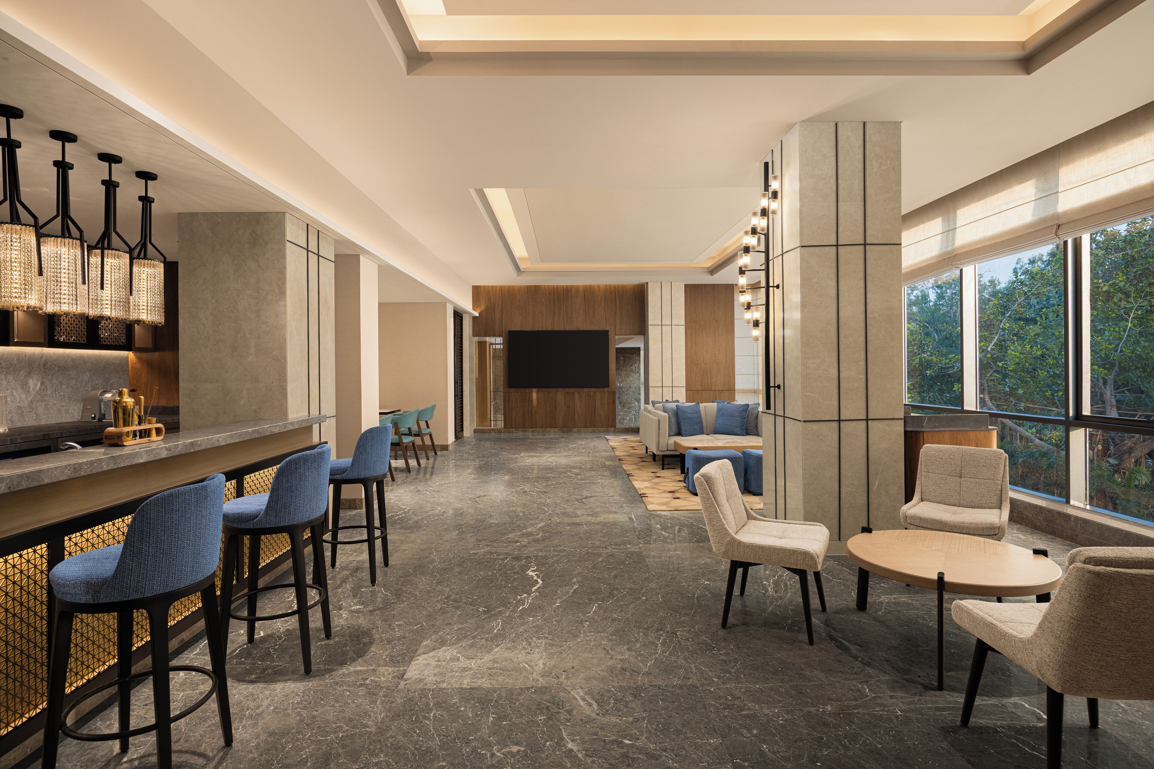 A modern bar area with high stools, a counter, and a large TV screen.