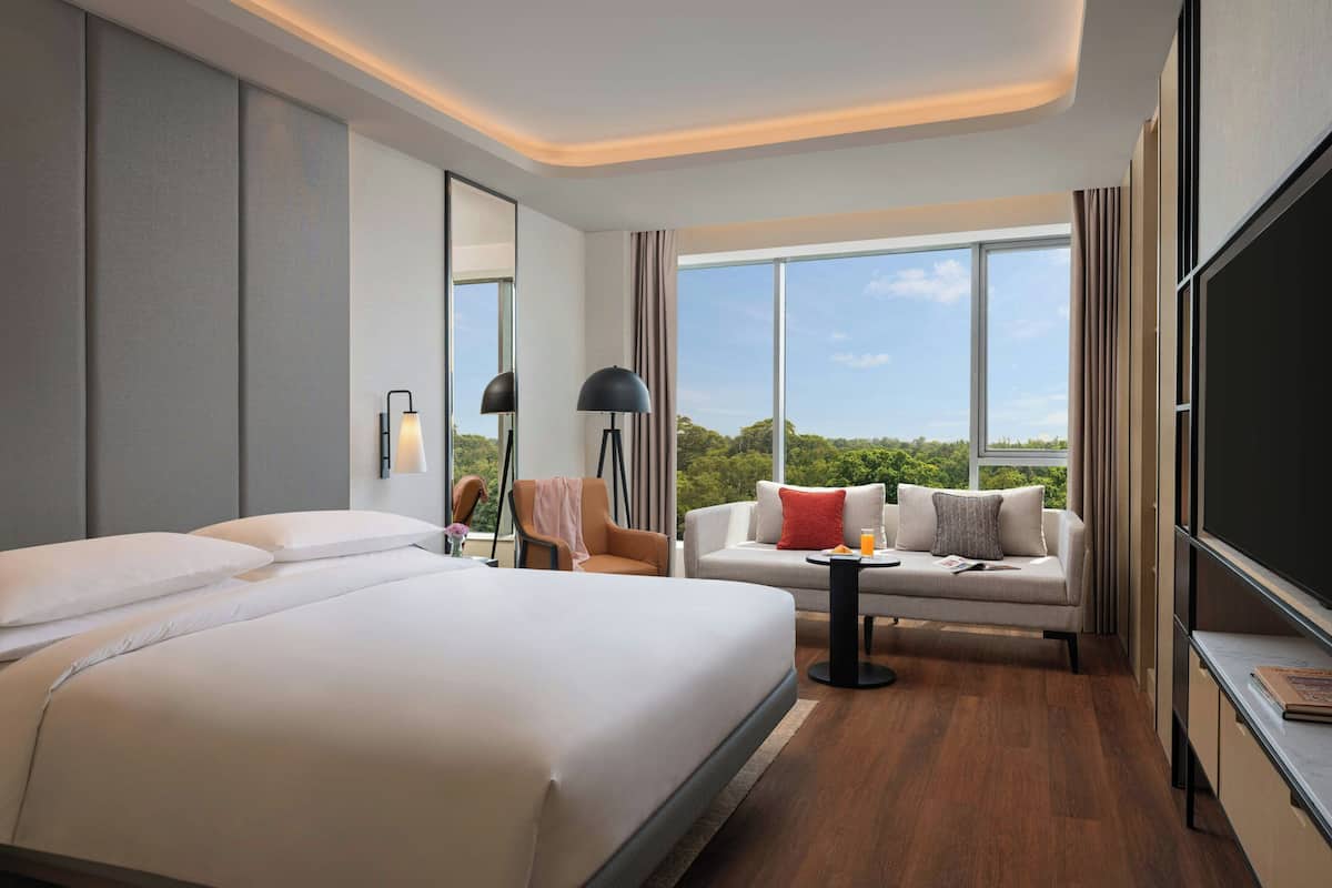 Een hotelkamer met een groot bed, een slaapbank, een kleintje tafeltje, een televisie en een raam met uitzicht over de stad.