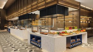 Una mesa de buffet moderna con múltiples estaciones de servicio, vitrinas de vidrio y una gran variedad de alimentos.