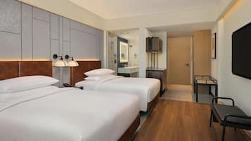Une chambre d’hôtel avec deux lits, une salle de bain, une télévision et un bureau.