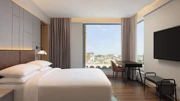 Une chambre d’hôtel moderne équipée d’un grand lit, d’un bureau, d’une chaise et d’un téléviseur.